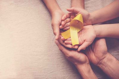 hands hold yellow ribbon representing childhood cancer awareness