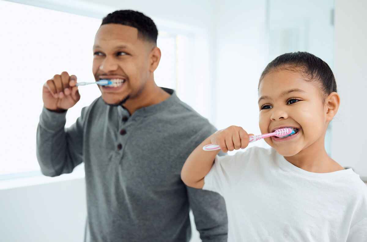 Father and daughter brush their teeth