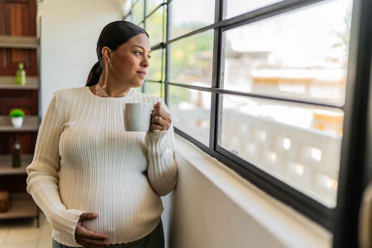 Pregnant woman looks out window