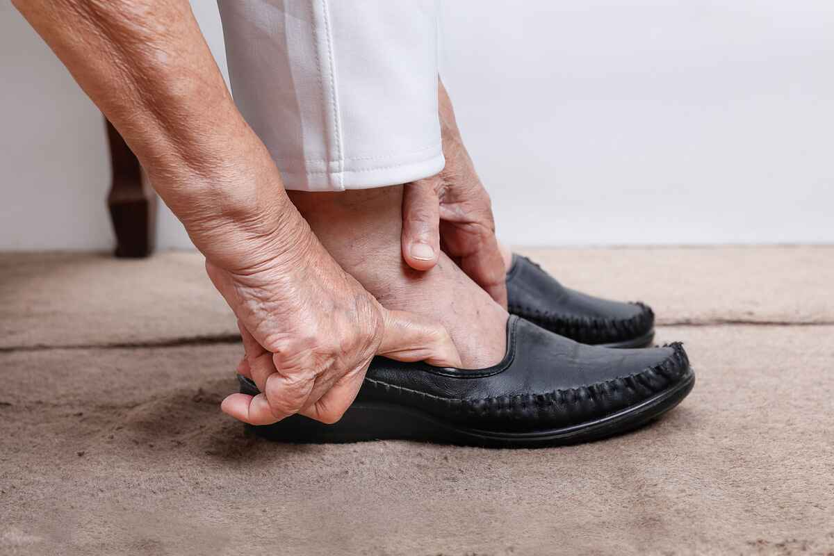 Elderly woman with swollen feet puts on shoes