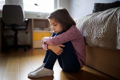 child sitting holding their knees