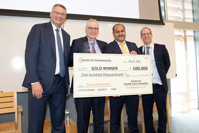Four men in a lobby holding a large check made out to "Gold Winner $100,000."